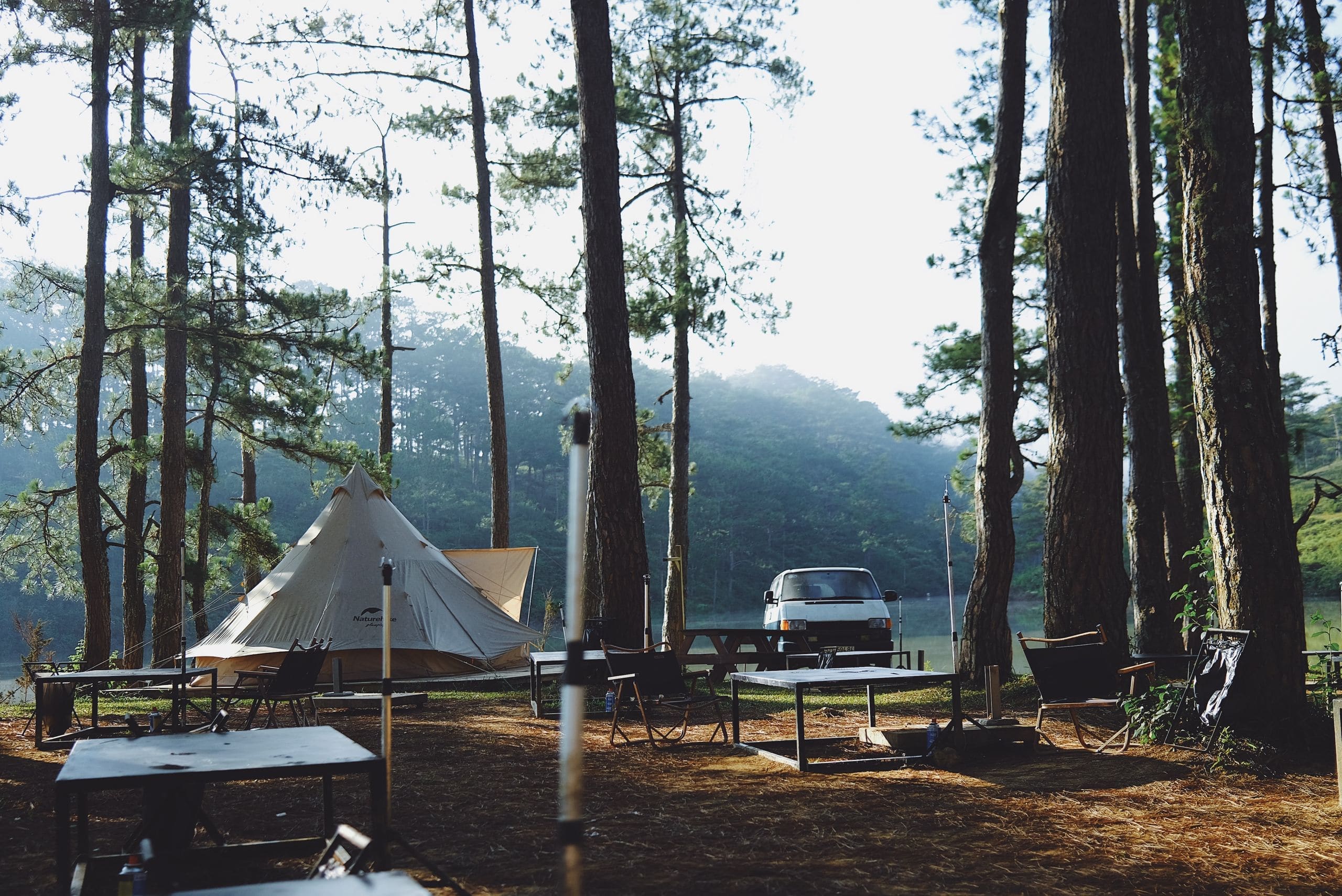 Glamping picnic tables with umbrellas and grills set up on the lawn in front of the cabins